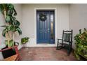 Inviting front porch with brick flooring, rocking chair, potted plants, and a charming blue front door at 1470 Atwater Dr, North Port, FL 34288