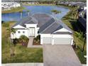 Aerial shot of a beautiful one-story home with lake view, a black roof, an oversized driveway and attached two-car garage at 15155 Scarlet Oak Ct, Punta Gorda, FL 33955