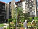 Exterior of the building with multiple screened balconies, beautiful landscaping, and walking paths at 21405 Olean Blvd # 605, Port Charlotte, FL 33952