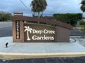 Elegant entrance sign for Deep Creek Gardens community with lush landscaping and illuminated signage at 25100 Sandhill Blvd # I201, Punta Gorda, FL 33983