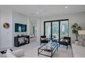 Bright, modern living room with sliding glass doors and comfortable seating arrangement, plus a glimpse into an adjacent bedroom at 27500 Janzen Ct, Englewood, FL 34223