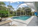 Private screened-in pool with waterfall, surrounded by lush landscaping and lounge chairs at 5017 Hanging Moss Ln, Sarasota, FL 34238