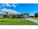 Charming single-story home boasts a well-manicured lawn, complemented by lush greenery and a convenient one-car garage at 61 Caddy Rd, Rotonda West, FL 33947