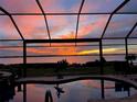 Screened-in lanai with pool overlooks the water at sunset at 12905 N Marsh Dr, Port Charlotte, FL 33953