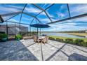 Screened-in patio with beautiful lake view, patio set with umbrella, and stunning blue skies at 15033 Spanish Point Dr, Port Charlotte, FL 33981