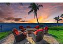 Relaxing outdoor seating area with stylish chairs, a cozy fire pit, and breathtaking waterfront views at sunset at 3790 Peace River Dr, Punta Gorda, FL 33983