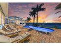 Inviting pool area with comfortable lounge chairs, a backdrop of palm trees, and tranquil waterfront views at sunset at 3790 Peace River Dr, Punta Gorda, FL 33983