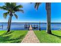 Waterfront property featuring a private dock extending into the serene water, framed by swaying palm trees and a well-manicured lawn at 3790 Peace River Dr, Punta Gorda, FL 33983