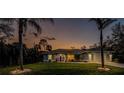 A lovely home at dusk, enhanced by swaying palm trees and manicured landscaping, creating a serene ambiance at 4529 Enid Ln, North Port, FL 34288