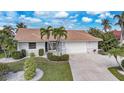 Charming home with a red tile roof, lush landscaping, and an attached two-car garage at 494 Monaco Dr, Punta Gorda, FL 33950