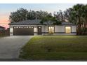 Beautiful single-story home with manicured lawn and inviting outdoor lighting at 5113 Weatherton St, North Port, FL 34288