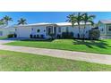Charming single-story home featuring well-manicured landscaping, lush lawn, and a white metal roof in a sunny, tropical setting at 621 Trabue Ave, Punta Gorda, FL 33950