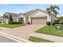 Charming single-story home with a well-manicured lawn, brick paver driveway, palm tree, and two car garage at 3860 Cobblestone Ln, Punta Gorda, FL 33980