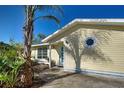 The exterior of the property showcases light yellow siding and a blue door, accentuated by lush tropical landscaping at 7341 Hart St, Englewood, FL 34224