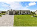 Well-maintained single-story home with green lawn, paver driveway, and beautiful landscaping at 12107 Gulfstream Blvd, Port Charlotte, FL 33981