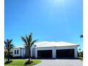 Front elevation of a modern-style home with a metal roof, well-maintained lawn, and contemporary garage doors at 1631 Casey Key Dr, Punta Gorda, FL 33950