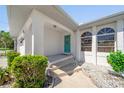 Inviting front porch with arched entryway, colorful door, and decorative landscaping at 18662 Arapahoe Cir, Port Charlotte, FL 33948
