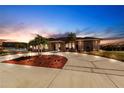 Well-maintained single story home with a circular driveway, palm trees, and accent lighting at dusk at 20339 Gentry Ave, Port Charlotte, FL 33952