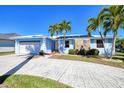 Inviting single-story home with a blue exterior, stone accents, mature palm trees, and an attached garage at 2180 Via Esplanade, Punta Gorda, FL 33950