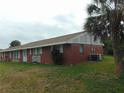 Side view of a brick multifamily residence with green lawns and mature trees at 20341 Midway Blvd, Port Charlotte, FL 33952