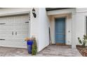Close-up of a blue front door with a brick walkway and a two-car garage to the side at 2486 Buckthorn Loop, North Port, FL 34289