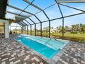 Relaxing screened-in pool with brick surround, overlooking a serene water view and lush greenery at 260 Long Meadow Ln, Rotonda West, FL 33947