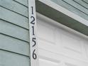 Close-up of a house number on the trim of the house next to a white garage door at 12156 Wellington Ave, Port Charlotte, FL 33981