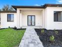 Stylish home entrance with a paved walkway, modern black double doors and black mulch accents at 14319 Allensworth Ave, Port Charlotte, FL 33981