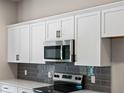 Modern kitchen features white cabinets, stainless steel appliances, gray subway tile backsplash, and white quartz countertops at 17323 Elmwood Ave, Port Charlotte, FL 33948