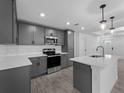 Contemporary kitchen featuring stainless steel appliances, gray cabinets, and stylish pendant lighting at 17331 Elmwood Ave, Port Charlotte, FL 33948