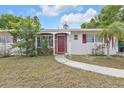 Inviting front porch with red door, decorative brick accents, and manicured landscaping at 22385 Olean Blvd, Port Charlotte, FL 33952