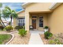 Inviting front entrance with a cozy seating area, decorative wreath, and meticulously maintained landscaping at 24321 Kintail Ct, Punta Gorda, FL 33980