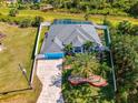 Aerial view of a beautiful blue home with a screened-in pool, and a spacious driveway at 1563 Arundel Ave, North Port, FL 34288