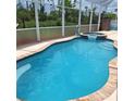 Inviting screened-in pool with an attached spa, surrounded by lush greenery, perfect for relaxation and outdoor enjoyment at 1563 Arundel Ave, North Port, FL 34288