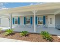 Inviting front porch with decorative blue shutters, freshly painted exterior, and manicured landscaping at 25413 Prada Dr, Punta Gorda, FL 33955