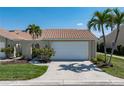 Charming villa features an attached garage, lush landscaping, and a classic red tile roof for a timeless Florida aesthetic at 2645 W Marion Ave # 114, Punta Gorda, FL 33950