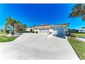 Well-maintained stucco home with a tile roof, palm trees, and a large driveway leading to an attached two-car garage at 740 Via Esplanade, Punta Gorda, FL 33950