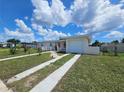 A view of a single-story home featuring a driveway and a well-kept lawn under a partly cloudy blue sky at 858 Conreid Ne Dr, Port Charlotte, FL 33952