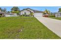 Landscaped home featuring an attached garage and driveway leading to the front of the house at 1353 Newton St, Port Charlotte, FL 33952