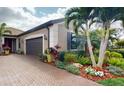 Charming home featuring a paver driveway, two-car garage, and tropical landscaping at 2436 Arugula Dr, North Port, FL 34289