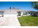 Front view of a bright, white single-story home featuring a two-car garage, a well-kept lawn and blue skies at 27250 Salta Dr, Punta Gorda, FL 33983