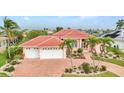 Home exterior with lush landscaping, a red tile roof, and a two-car garage at 480 Macedonia Dr, Punta Gorda, FL 33950