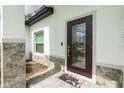Close up of front door featuring stone accents, a glass paneled door and a welcoming mat at 1384 Alpinia Rd, North Port, FL 34288