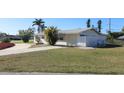 A single-story home with white exterior, a driveway, and well-kept lawn on a sunny day at 22191 New Rochelle Ave, Port Charlotte, FL 33952