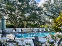 Relaxing community pool area with lounge chairs, tables, and lush greenery, perfect for leisure and enjoyment at 238 Southampton Dr # 319, Venice, FL 34293