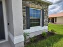 Detailed view of a home's exterior featuring a window with decorative shutters and stone accents at 354 Porto Alegre St, Punta Gorda, FL 33983