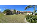 Charming one-story home with lush landscaping, including palm trees and flowering bushes in the front yard at 569 Royal Poinciana, Punta Gorda, FL 33955