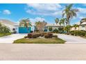 Beautifully landscaped home showcasing vibrant blue accents and a circular driveway, complete with palm trees and lush greenery at 103 Colony Point Dr, Punta Gorda, FL 33950