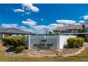 A welcome sign for Maine Way Villas featuring lush green bushes under a partly cloudy blue sky at 1408 San Cristobal Ave # 4, Punta Gorda, FL 33983