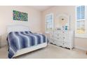 Bright bedroom with white wicker furniture, plantation shutters, and a plush blue and white striped bedding set at 17094 Acapulco Rd # 312, Punta Gorda, FL 33955